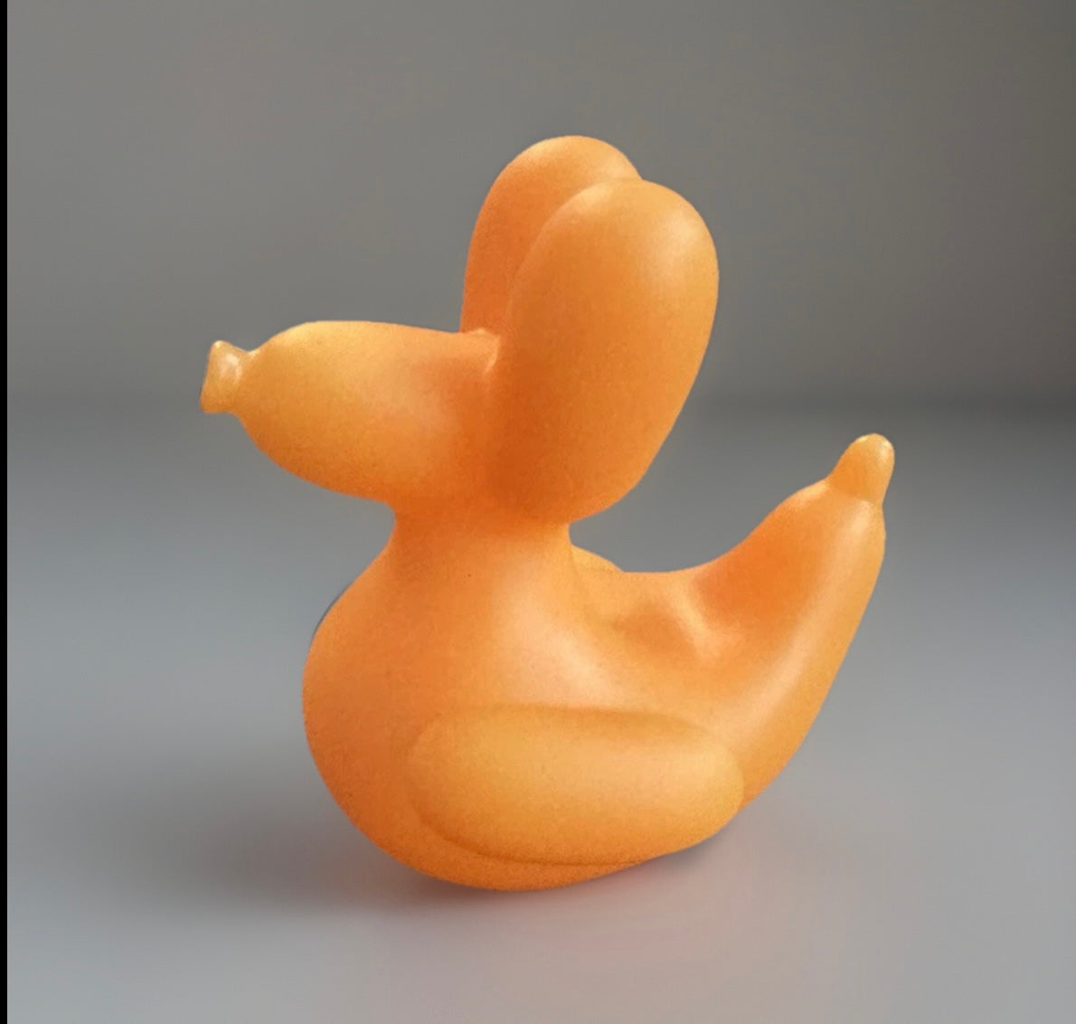 Orange balloon animal rubber duck toy with smooth texture and unique design on gray background