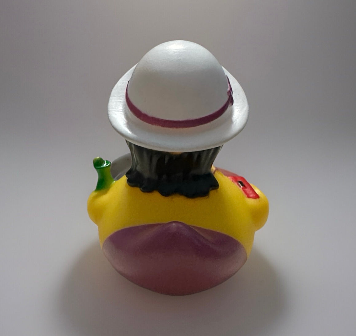 Rear view of party girl rubber duck wearing white hat and holding a green bottle from Reed’s Rubber Ducks and Sensory Shop