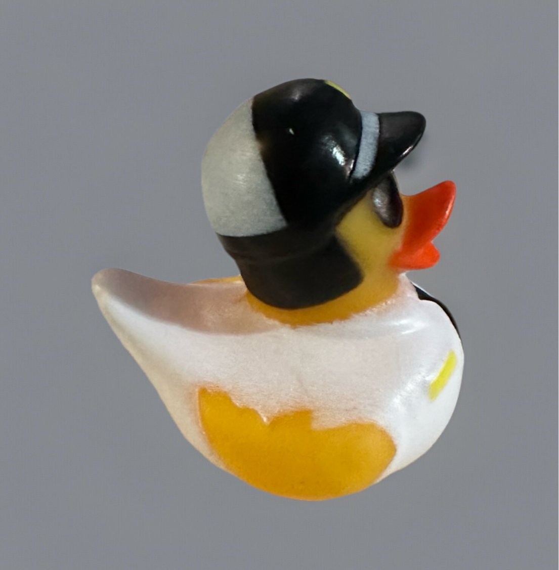 Police rubber duck wearing a black and white police hat with an orange beak on gray background