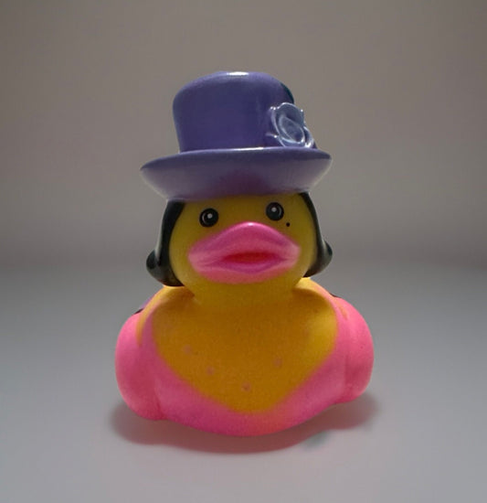 Yellow rubber duck with pink wings wearing a purple top hat rubber duck with black hair and bright pink lips