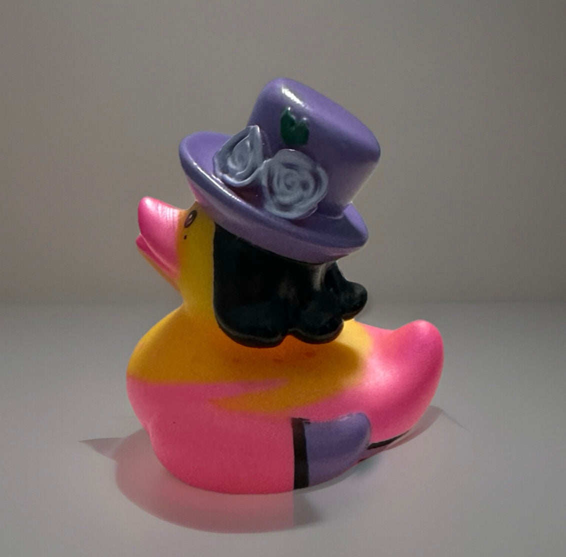 Purple top hat rubber duck with decorative roses and vibrant pink and yellow colors