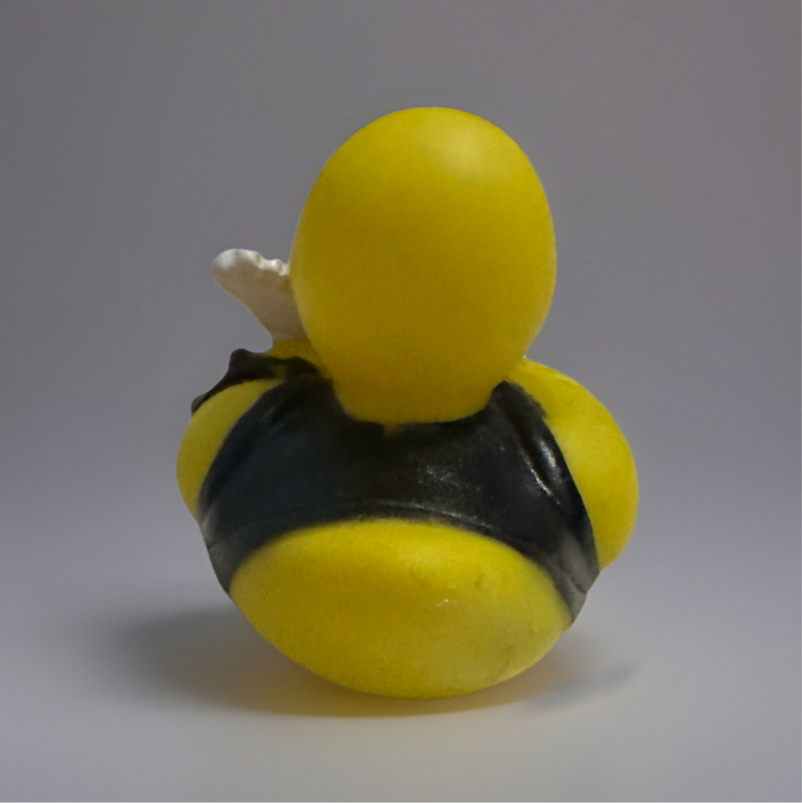 Rear view of rock and roll rubber duck wearing black leather vest with white guitar