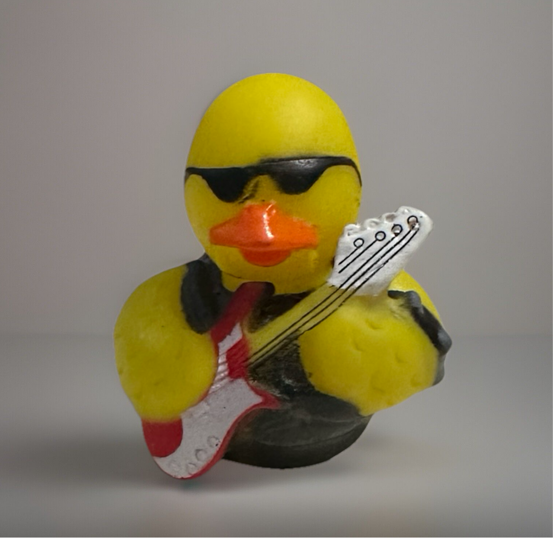 Rock and roll rubber duck wearing sunglasses and holding a red and white electric guitar
