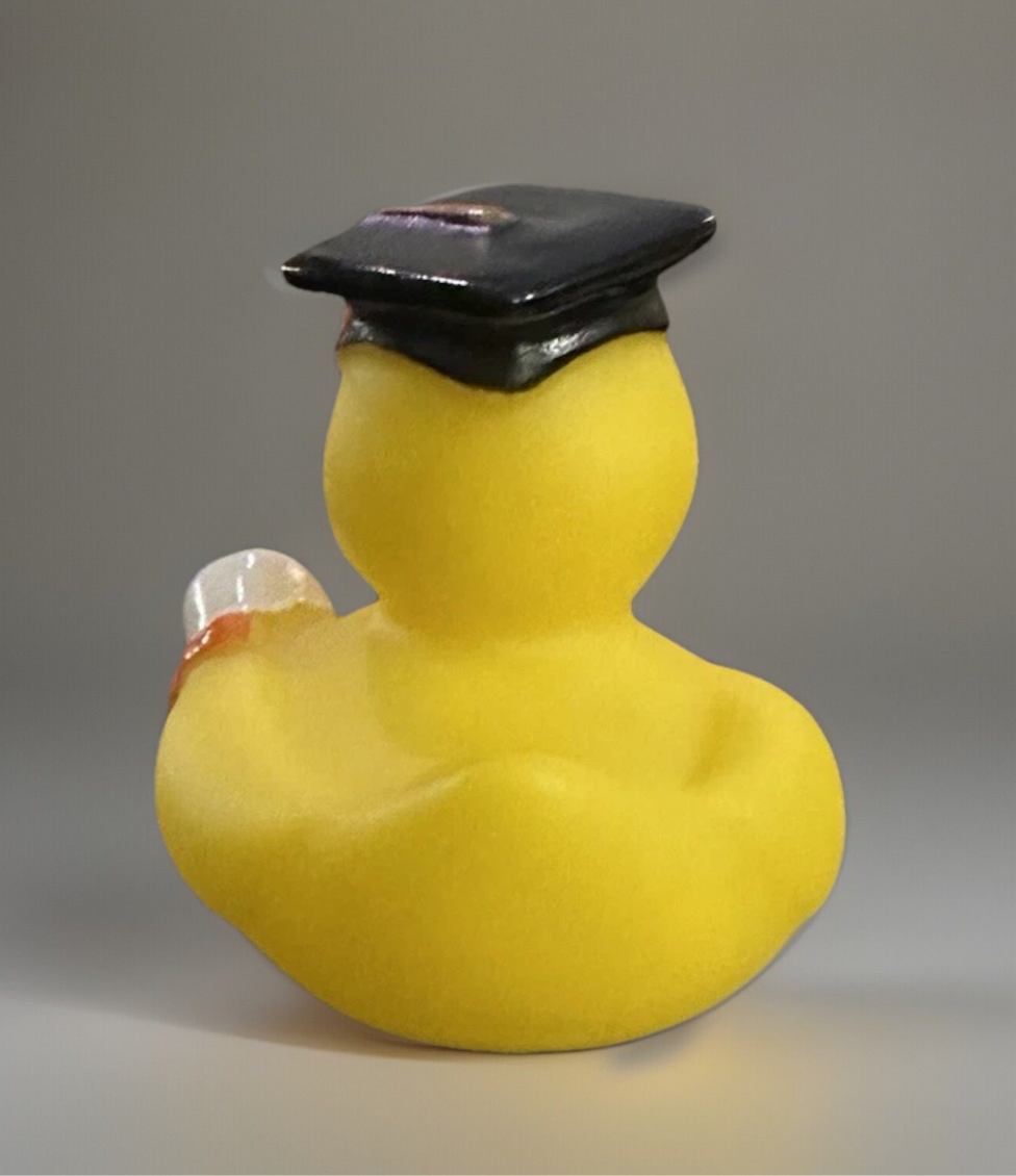 Yellow 2 inch graduation duck wearing a black graduation cap holding a diploma from Reed’s Rubber Ducks and Sensory Shop