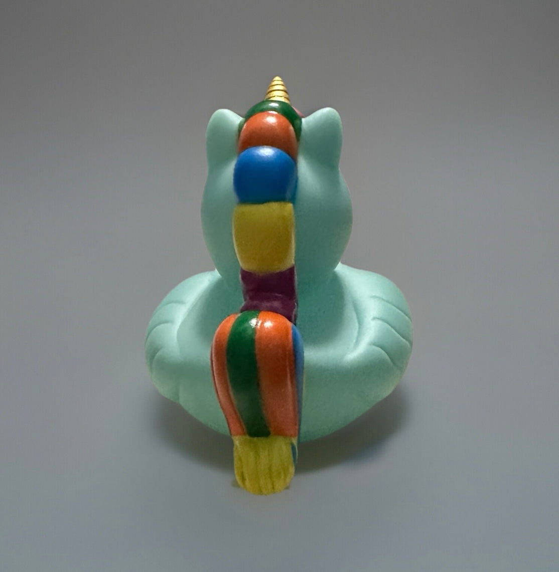 Sea foam unicorn rubber duck with a colorful striped mane and golden horn rear view